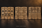 Assembly concept render of three separate four-panel birch miniature folding screens: Chrysanthemum and Fan, Sakura and Lattice, and Waves and Pine, on a black and ochre gallery-style tabletop.