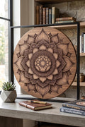 A round wooden wall plaque featuring a laser-engraved lotus mandala design, displayed on a desk with books and a small potted succulent.
