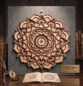 A 3D layered wooden celestial mandala wall art piece mounted on a dark textured background above an open book, compass, and inkwell on a wooden desk.
